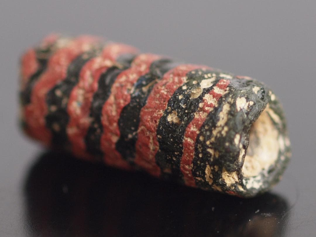 大型の漆黒管玉に、赤茶の螺旋紋と細く浅い引っ掻き紋1-4Cローマン・ビーズ銀化も